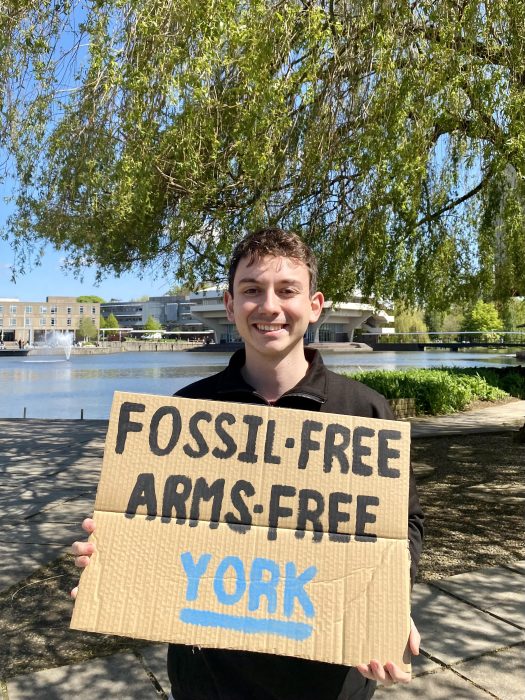 Pierrick Roger holding cardboard sign saying 'fossil free, arms-free York'