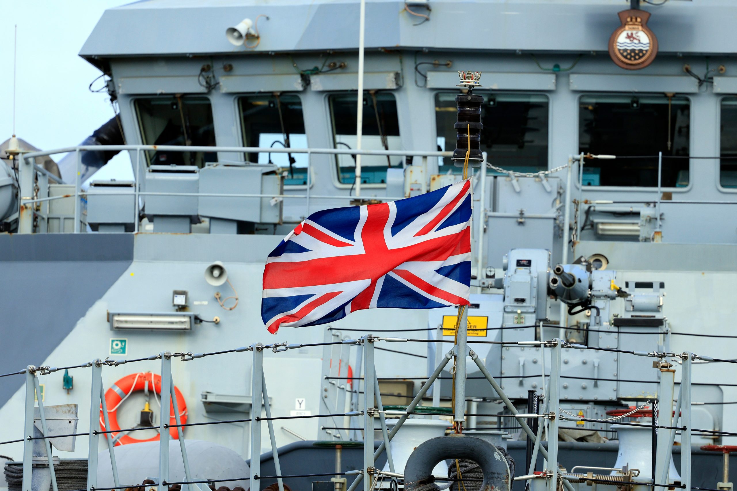 Royal Navy ship with a Union Jack flag flying in the foreground